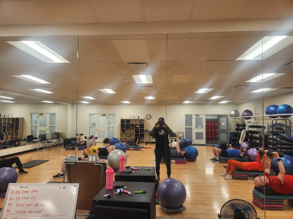 Group exercise class participants moving together in a bright gym